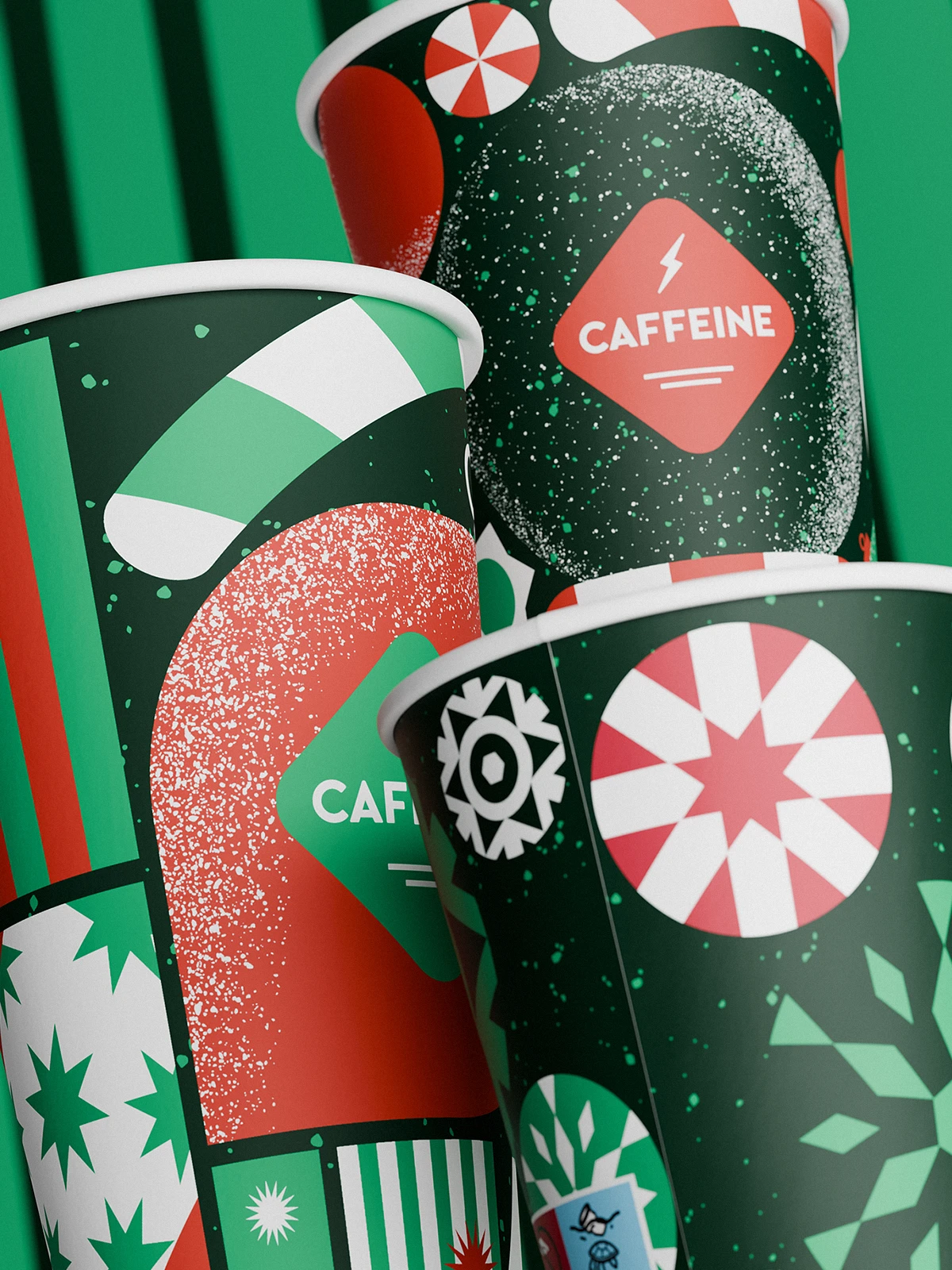 Close-up of stacked CAFFEINE holiday cups (2023 edition) with bold red, green, and white festive patterns. The designs feature candy shapes, stars, stripes, and snowflake motifs, with the CAFFEINE logo centered in a diamond frame.