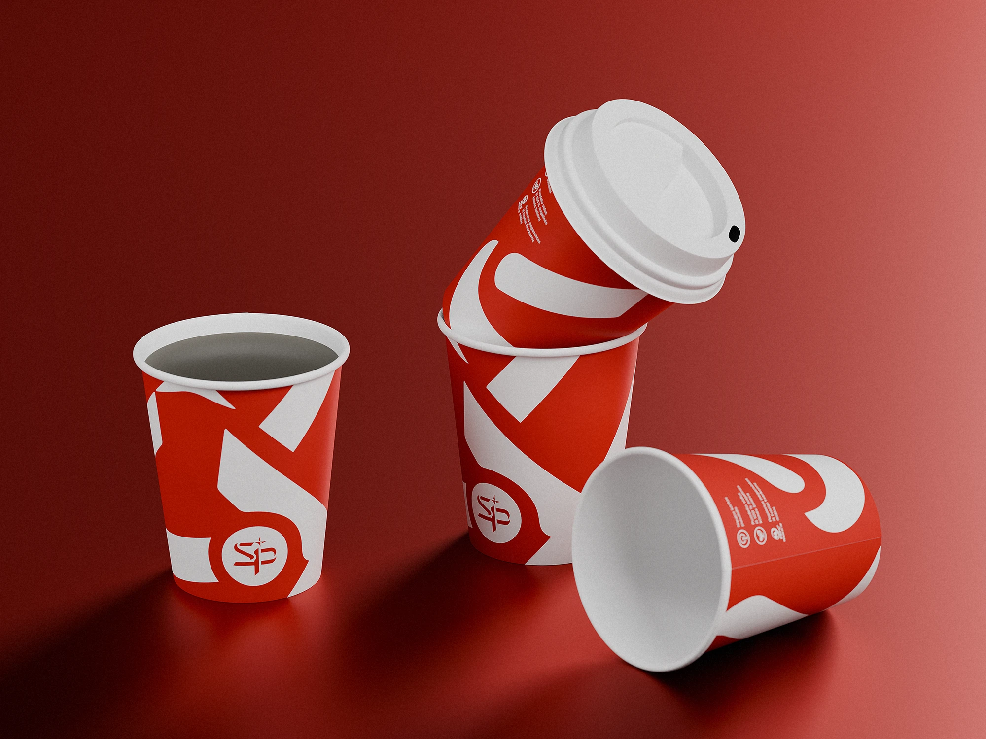 Three red and white paper coffee cups with bold graphic patterns and the Lietuvos Spauda logo, arranged on a red surface with one cup stacked inside another and one lying on its side.